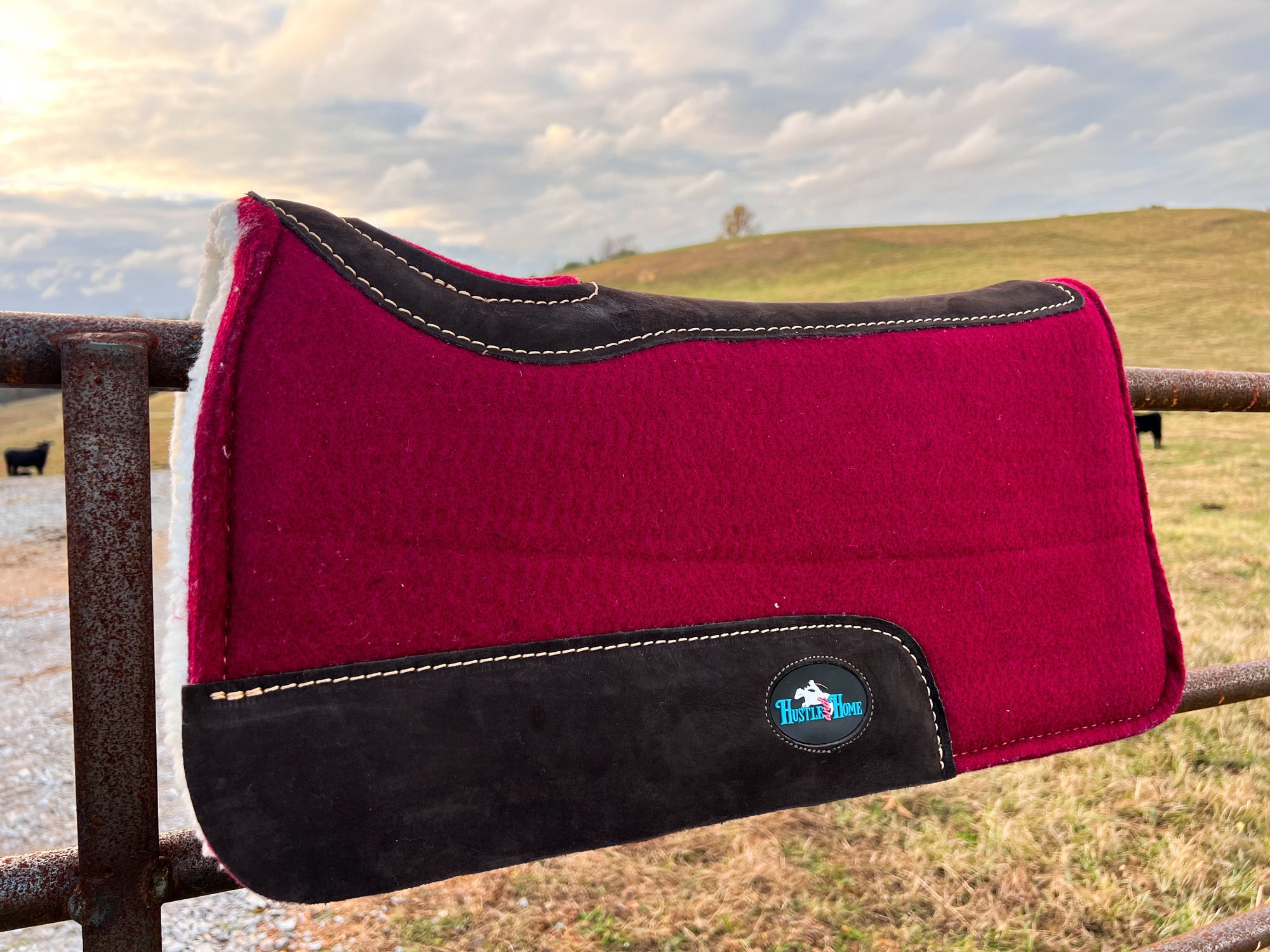 Western wool saddle pad styled on ranch fence at golden hour